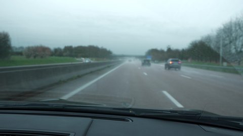 4K 60p Close-up Windshield Wipers Sweeping across Wet Windscreen with Raindrops. Driving Car During Rain. Moving Along Highway. Country road. France Europe