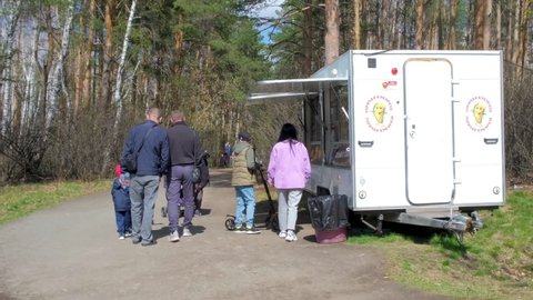 CHELYABINSK, Russia-03.05.2021: People walk in the city eco-park and buy food in the Food Truck on a sunny spring day.