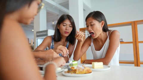 Group of Beautiful Asian woman friendship eat tasty cake and dessert on the table in cafe together. Female girl friends talking and enjoy eating sweet bakery and beverage in restaurant with happiness