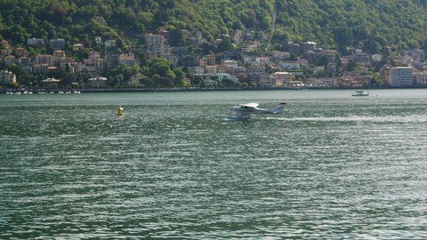 May 3, 2021, Como, Italy - A seaplane (or floatplane) floating on the waters of Lake Como. Hills with green trees on the background.