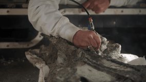 This video features the hands of a skilled archaeologist paleontologist using drills and tools to study dinosaur fossils.