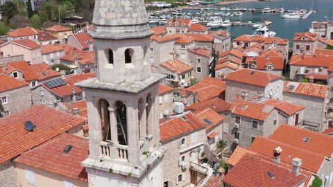 Old medieval town stone houses (Mediterranean architecture) - red roofs and church bell tower. Budva is the center of tourism in Montenegro and summer vacation destination. Aerial drone cityscape.