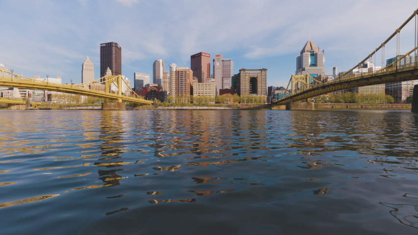 Pittsburgh city skyline lit up by the setting sun with the river and bridges in the foreground