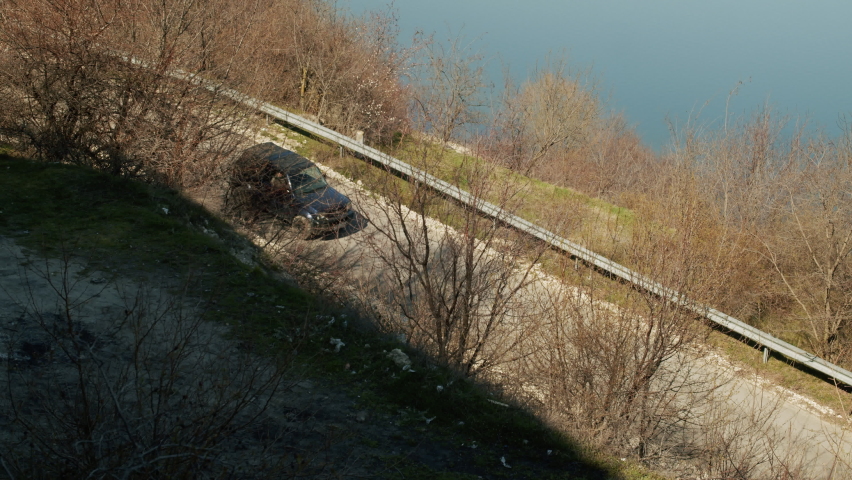 View of the mountain road that passes through the forest and rocks. Summer landscape with a curved road and green trees and a river in a hilly region.
