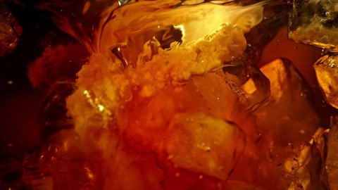Super Slow Motion Shot of Pouring Cream into Cold Coffee Whirl with Ice Cubes at 1000fps.