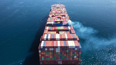 Aerial drone flight above huge colourful container carrier ship cruising deep blue open ocean sea Video stock