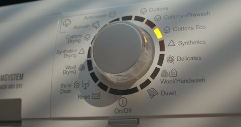 Laundry Setting Washing Machine Dial to ECO Mode for Energy Saving and Environmental Conservation in Bathroom