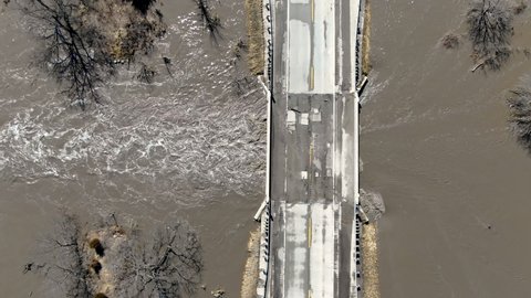 Top down view of flooded river running under bridge. Drone top view.