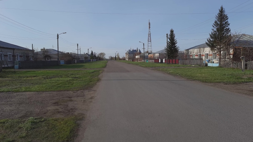 Paved road with adjacent green areas and residential buildings. Morning time in the spring.