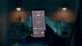 Man holding smartphone with active smart home application switching on light. Person tapping on screen for turning on the lights in house with automation lighting system starting to work at laptop - Powered by Shutterstock - Get 15% off with code: PIKWIZARD15