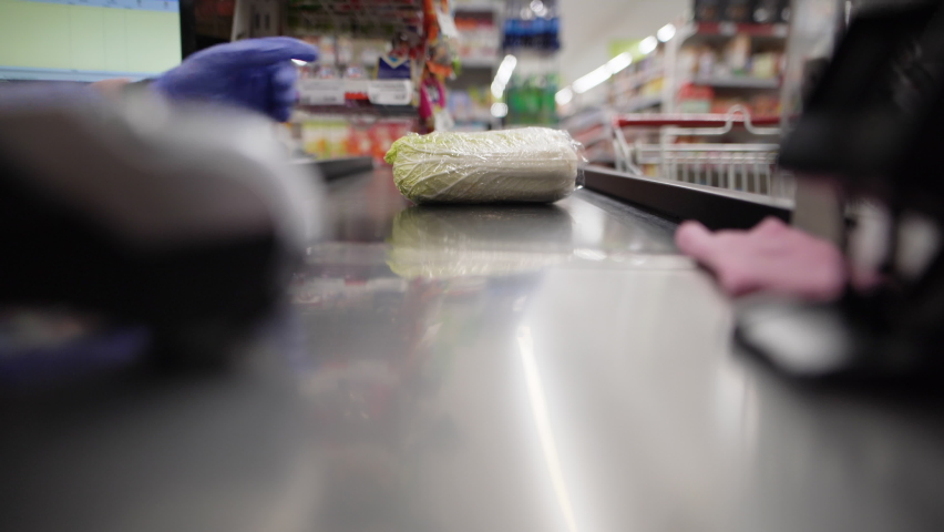 close-up of a customer placing goods on a conveyor belt at the checkout counter. Purchase of fruits and vegetables. Royalty-Free Stock Footage #1071935665
