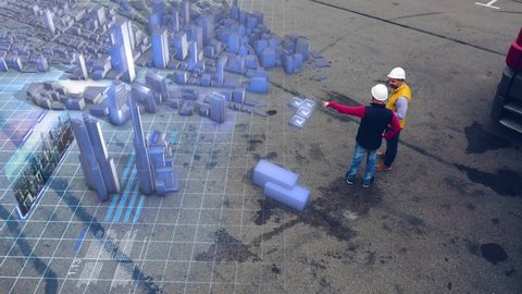 AERIAL. Two workers discussing city construction using hologram technology. Top view of the holograms city. 