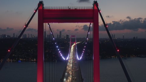 Epic Dolly forward through Istanbul Bosphorus Bridge Arch Illuminated in Red light at Night with Car traffic, Aerial Drone