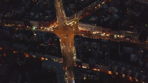 Aerial Birds Eye View over Berlin, Germany Neighborhood, intersection at night with glowing street traffic city lights at Rosenthaler Platz, Top View of Cityscape at Night