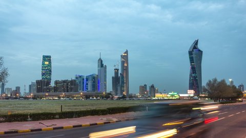 Kuwait City skyline with Skyscrapers day to night transition timelapse in downtown illuminated at dusk. View from road with traffic. Kuwait City, Middle East.