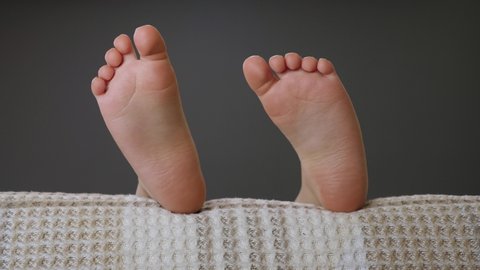 Comfort feet concept. Little girl sleeping in bed. Child feet in bed comfortable. Cute child legs in bed. Sleeping child feet close up toes move. Pair of legs closeup. Barefoot kid sleeping in sofa