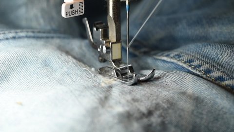 close up of sewing for repair blue denim jeans with machine. handmade garment industrial concept. process of sewing clothes on sewing machine. Close-up of needle for sewing. Slow Motion