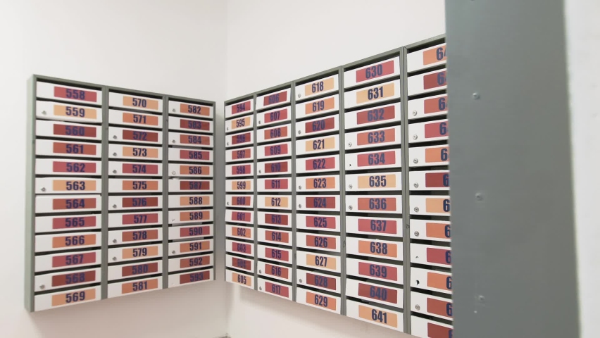 There are many colorful mailboxes in the lobby of a residential building with apartment numbers.