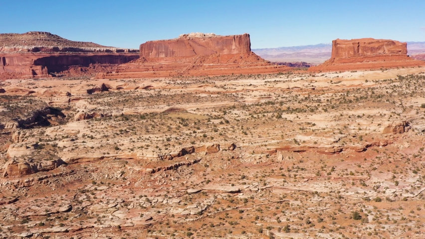 Merrimac and Monitor Buttes on Sunny Day. Aerial View. Grand County, Utah, USA. Drone Flies Sideways, Tilt Up