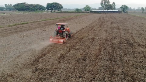 Aerial view tractor working on empty rice plantation field prepare for new paddy rice plant: film stockowy
