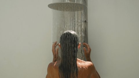 Young woman taking a tropical shower. Female showering in tropical private villa. Luxury resort lifestyle 