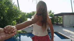 Young couple holding hands woman leading boyfriends walking towards pool deck at sunset in her private beach bungalow. POV travel concept. Couple on honeymoon checking into luxury hotel  - Powered by Shutterstock - Get 15% off with code: PIKWIZARD15