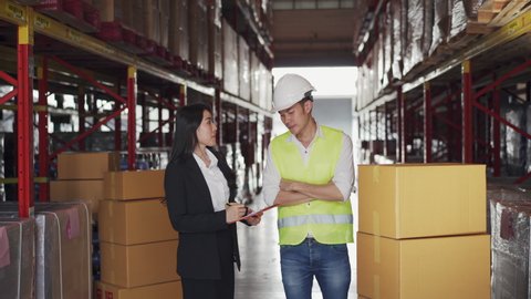 Asian female manager discussion with male warehouse worker about inventory storage plan in distribution fulfillment center. Business factory industry and freight transportation logistic concept.: film stockowy