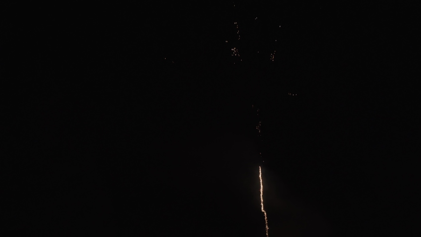 Multicolored fireworks balloons take off and explode against the black night sky. Festive pyrotechnics close-up.