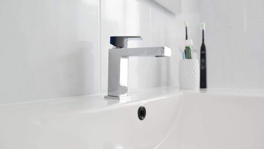 Hand turning water tap for pouring water into sink in bathroom.  Adult man turning on tap. Male hand turning water tap for pouring water into sink in  Royalty-Free Stock Footage #1071969574