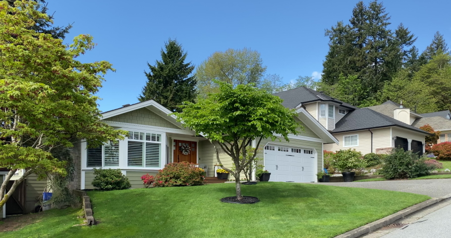 Establishing shot of two story stucco luxury house with garage door, trees and nice landscape in Vancouver, Canada, North America. Day time on September 2020. Still camera view. ProRes 422 HQ.