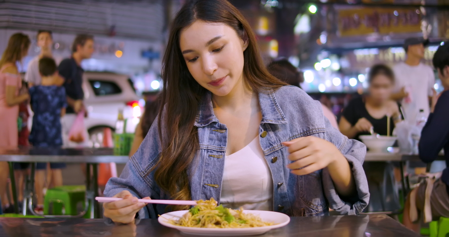 Young attractive asian woman enjoying street food on a night market in Thailand. Thai food concept. Asian food concept Royalty-Free Stock Footage #1071977968
