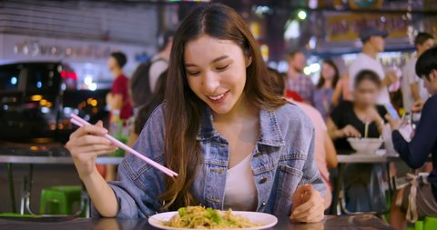 Young attractive asian woman enjoying street food on a night market in Thailand. Thai food concept. Asian food concept