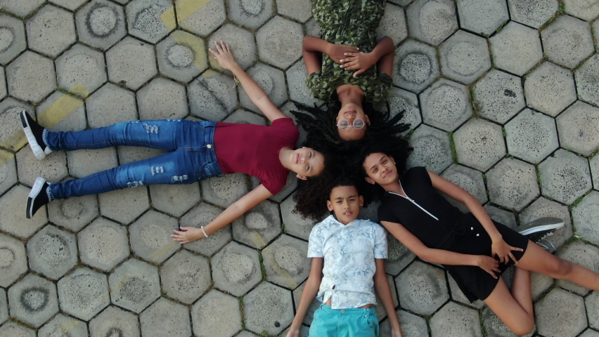 Children seen from above on lying on ground staring at the sky
