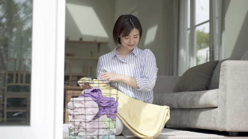 Young asian woman folding towel in the living room | Shutterstock HD Video #1071990712