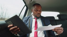 Successful handsome african american businessman in formalwear networking on digital tablet, analyzing financial data and charts while riding in backseat of car during business travel. - Powered by Shutterstock - Get 15% off with code: PIKWIZARD15