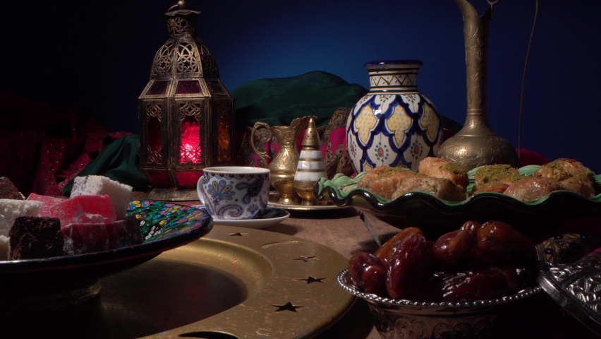 A night in the holy Muslim month of Ramadan. Iftar or suhur food on the table. Traditional oriental sweets and dates. Eid Mubarak. Eid al-Fitr | Shutterstock HD Video #1071993421