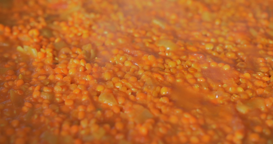 Indian cooking : Red Lentil Dhal. Close up of vibrant red lentils simmering. Professional asian exotic recipe. Royalty-Free Stock Footage #1071994378