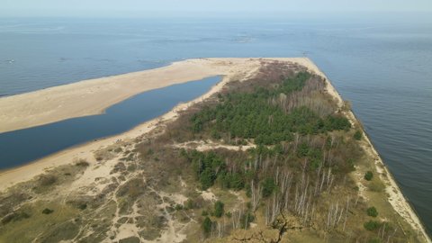 Beautiful aerial footage of Vistula River entering Baltic sea at Mewia Lacha Nature Reserve during a sunny day, Aerial side flight shot