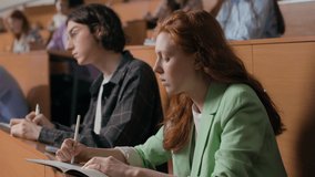Group of students learns at lecture room. Young people study in university or pupil sitting at school lesson. Teens listen to teacher and write at auditorium. Modern education indoors of college hall - Powered by Shutterstock - Get 15% off with code: PIKWIZARD15