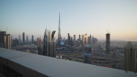 Tall modern glass skyscrapers in urban city center of Dubai during sunset. Burj Khalifa and busy city traffic on a highway in Dubai, UAE in 2021