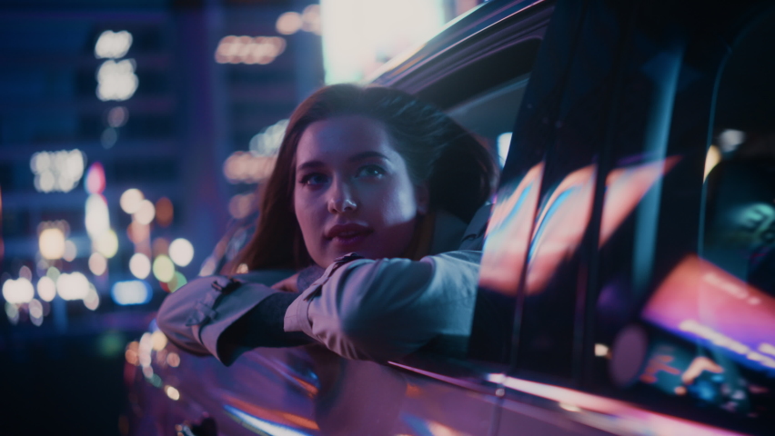 Excited Young Female is Sitting on Backseat of a Car, Commuting Home at Night. Looking Out of the Window with Amazement of How Beautiful is the City Street with Working Neon Signs. Cinematic Footage. Royalty-Free Stock Footage #1072002829