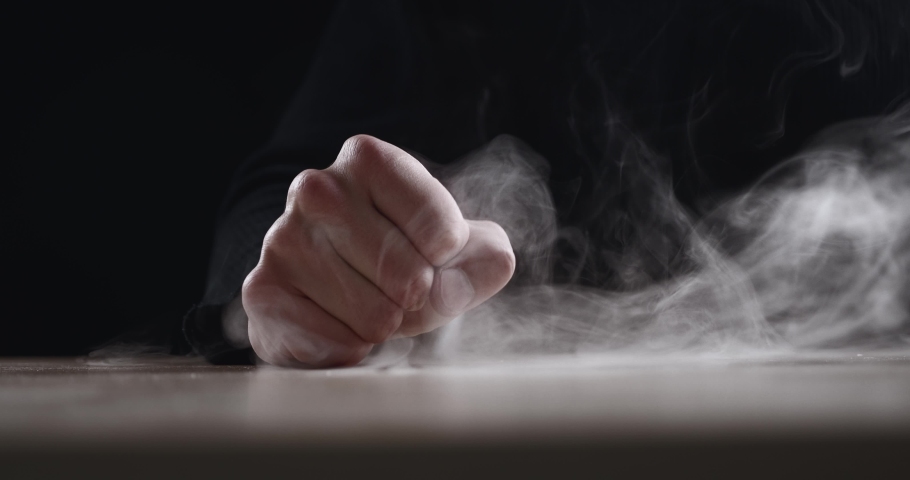 Close up evil man beats his fist on the table showing aggression on dark background. Terrible man's fist with fury hitting the table. Concept of anger. | Shutterstock HD Video #1072003465