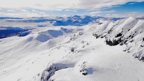 Stunning aerial view of a snow capped mountain range in the Nordic wilderness on a cold winters day. Aerial video.