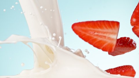 Super slow motion of strawberries falling into cream.