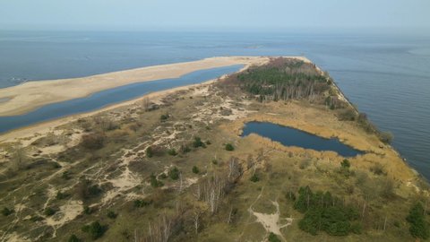 Aerial back motion shot of Mewia Lacha Nature Reserve during a sunny day and blue Baltic Sea in the background, Poland