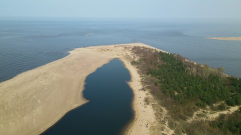 Drone flying sidewards showing beautiful sandy banks of Vistula River entering in Baltic sea, Poland daytime sunny weather at Mewia Lacha Nature Reserve 