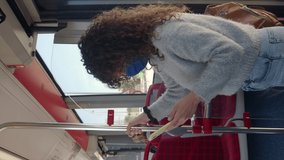 Vertical video.Tourist woman with medical mask traveling on a bus while chatting with a smartphone. Traveling in a time of pandemic	