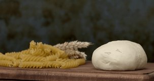 Slow motion of raw pasta in the glass bowl on wooden table background. 4K.