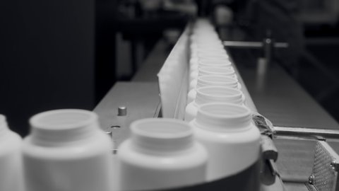 Production of dietary supplements. White plastic cans for tablets on a production automatic conveyor line. Bottle containers. Fish oil, Omega 3 or D-3 pills and nutraceutical for a healthy lifestyle.