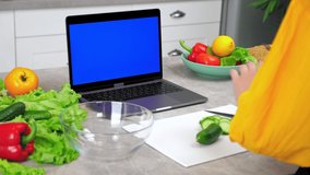 Blue screen mock up chroma key monitor display laptop: Woman housewife in home modern kitchen greets tells listen chef teacher, study online video call chat webcam computer. Distance cooking course
